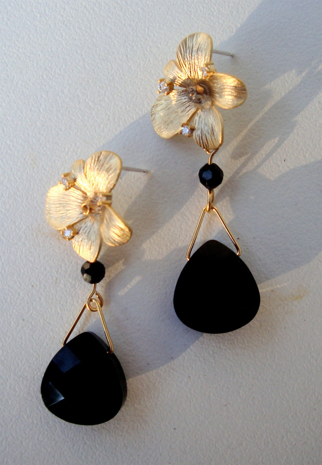 Matte gold over brass Orchid floret earring with a jet black  swarovski crystal briolette. The flower is adorned with tiny cz's.