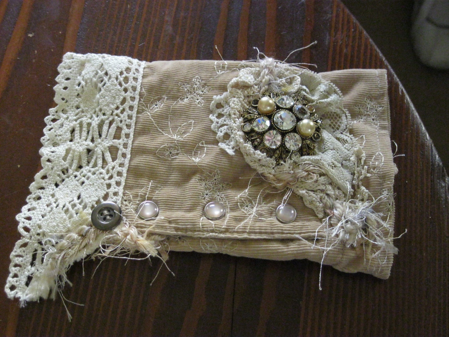 Unique fun wristlets.  Made from a cutoff wrist from a lightweight corduroy shirt and embellished with lace, yarn, old brooch & buttons.