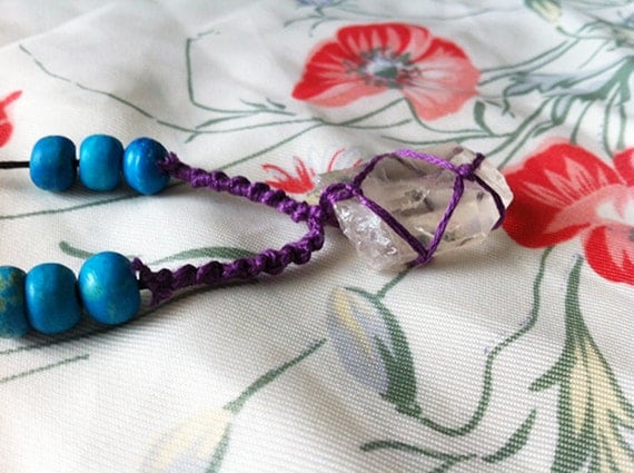 kai. netted quartz crystal necklace with wooden turquoise beads and purple thread.